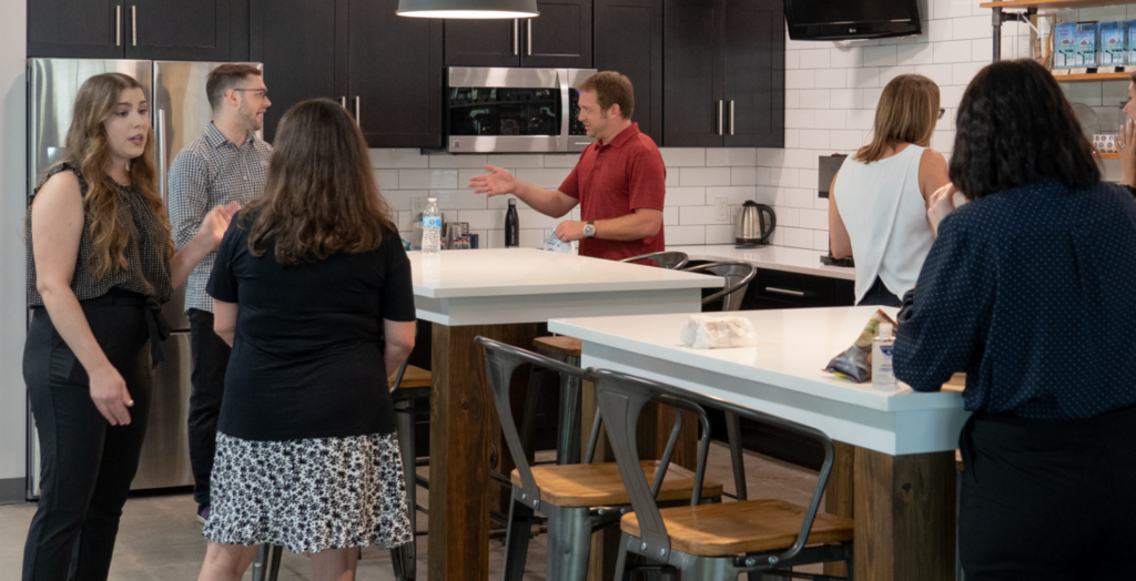 Clients and team chatting in office kitchen